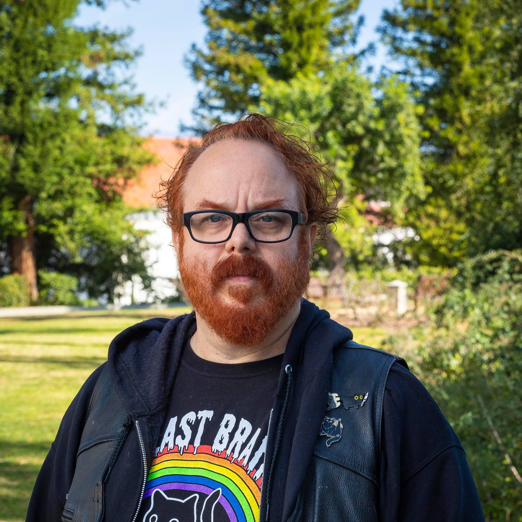 a person with red hair and beard standing in front of trees