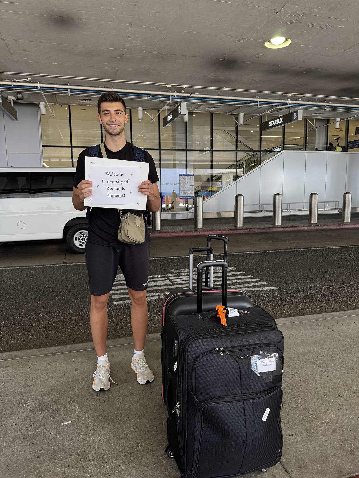 a person holding a sign and standing next to luggage