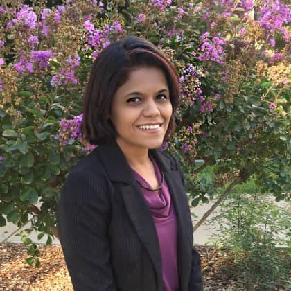 a person smiling in front of purple flowers
