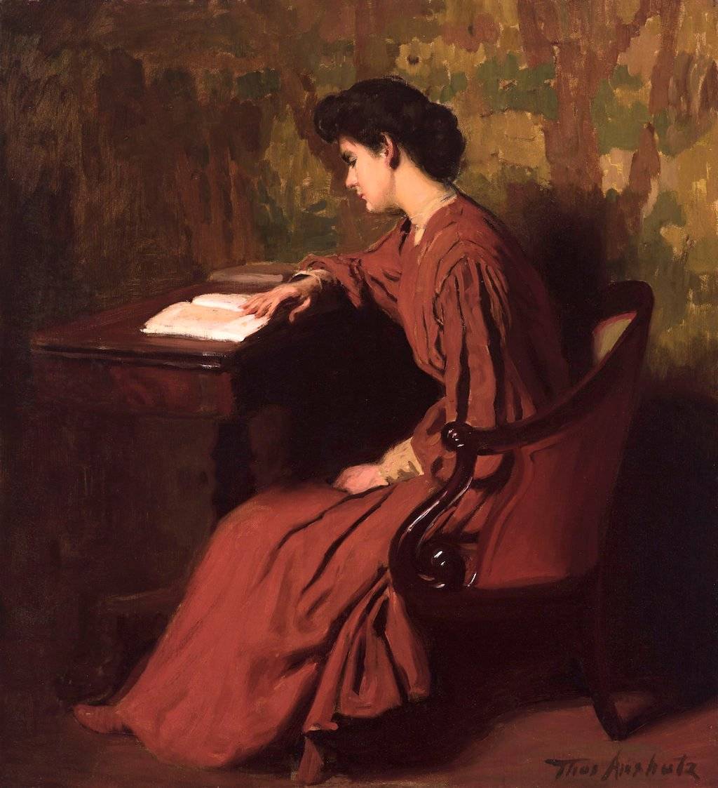 a person sitting at a desk reading a book