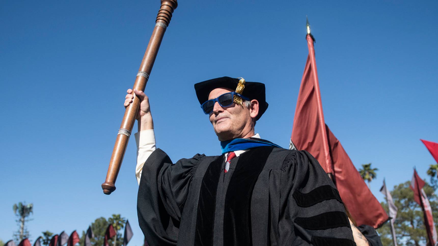 a person in a graduation gown holding a baton