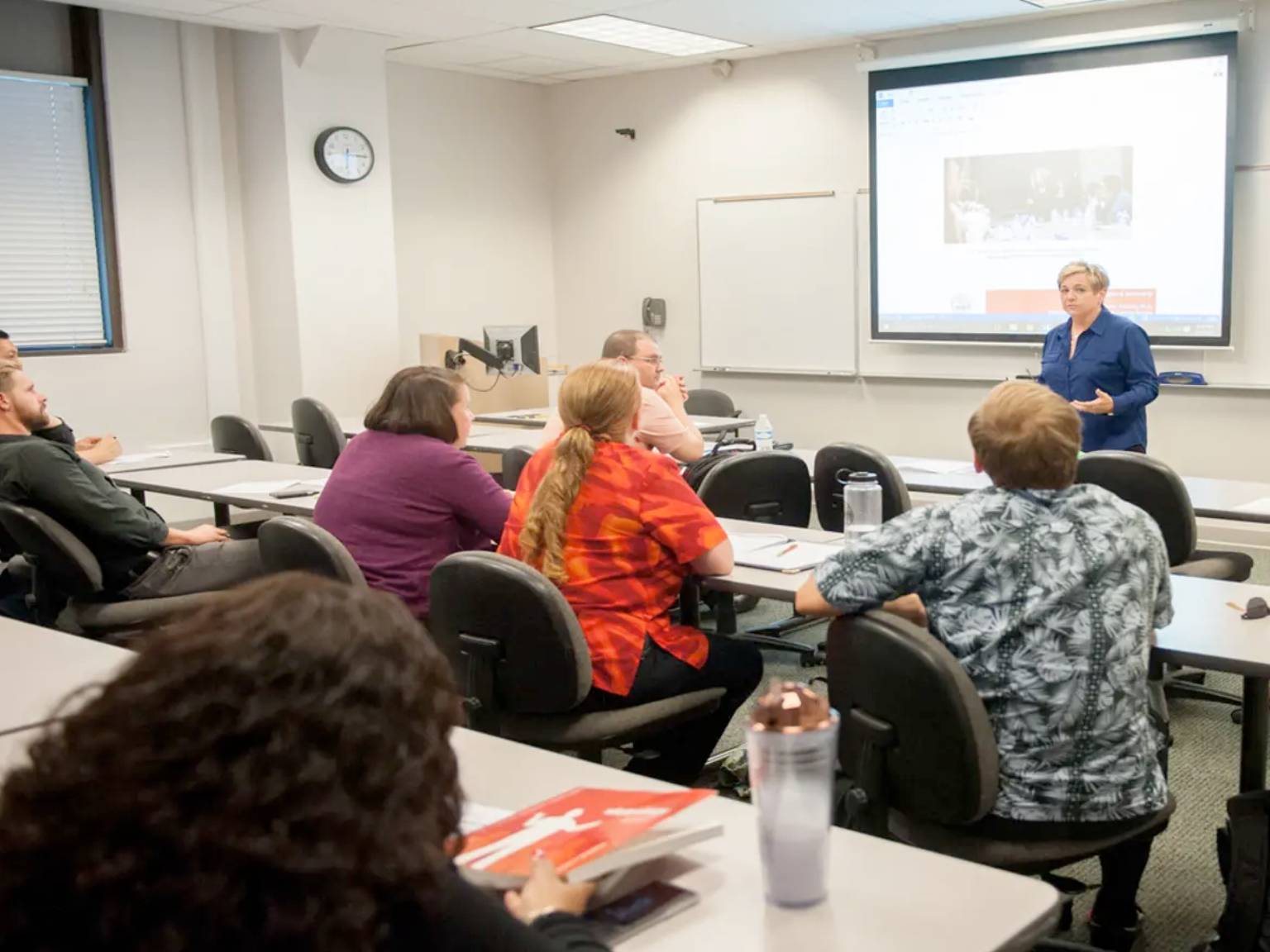 a person standing in front of a screen in a classroom