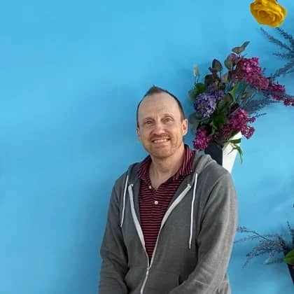 a person standing in front of a blue wall with flowers