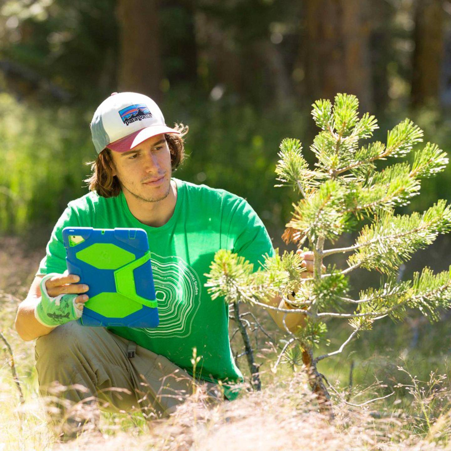 a person sitting in the woods holding a tablet
