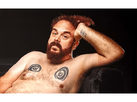 a person with a beard and mustache with tattoos on his chest