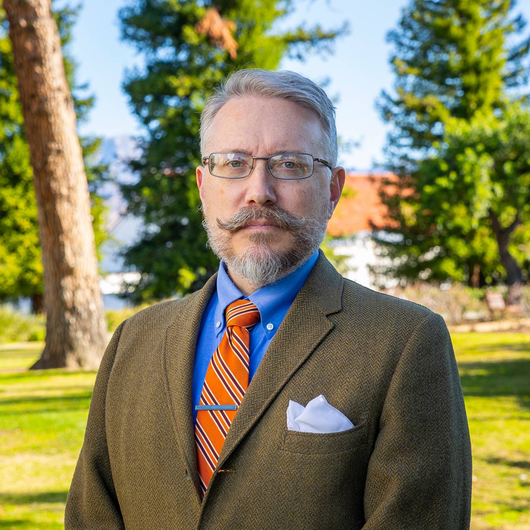 a person with a beard and mustache wearing a suit and tie