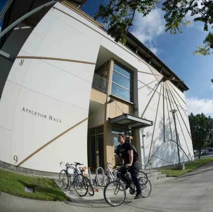 a person standing on a bicycle outside of a building