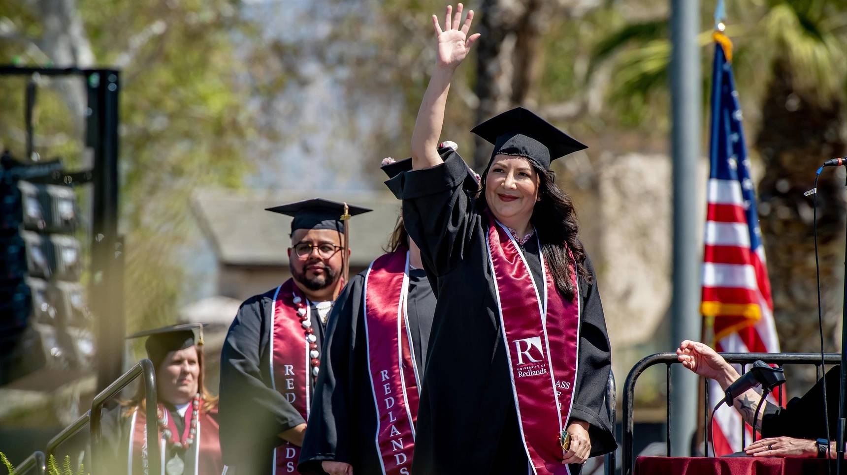 a person in graduation gown waving