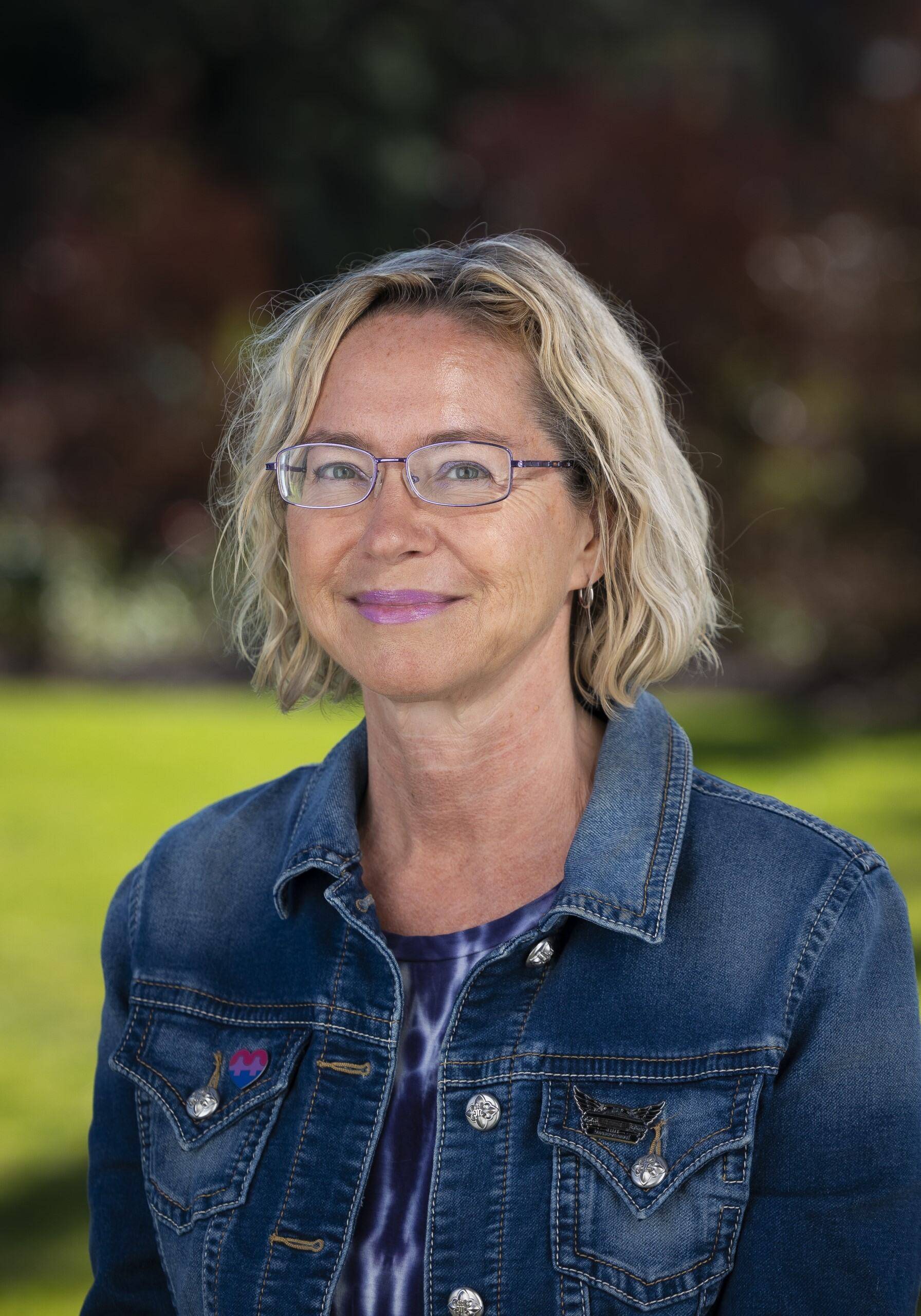 a person wearing glasses and a denim jacket