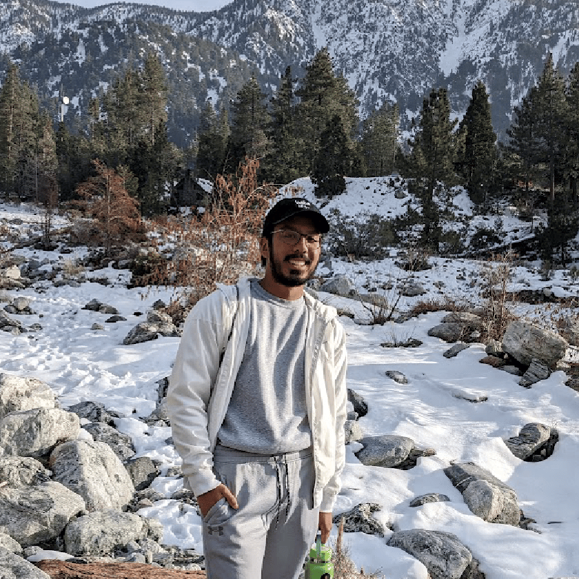 a person standing in snow with trees and mountains in the background