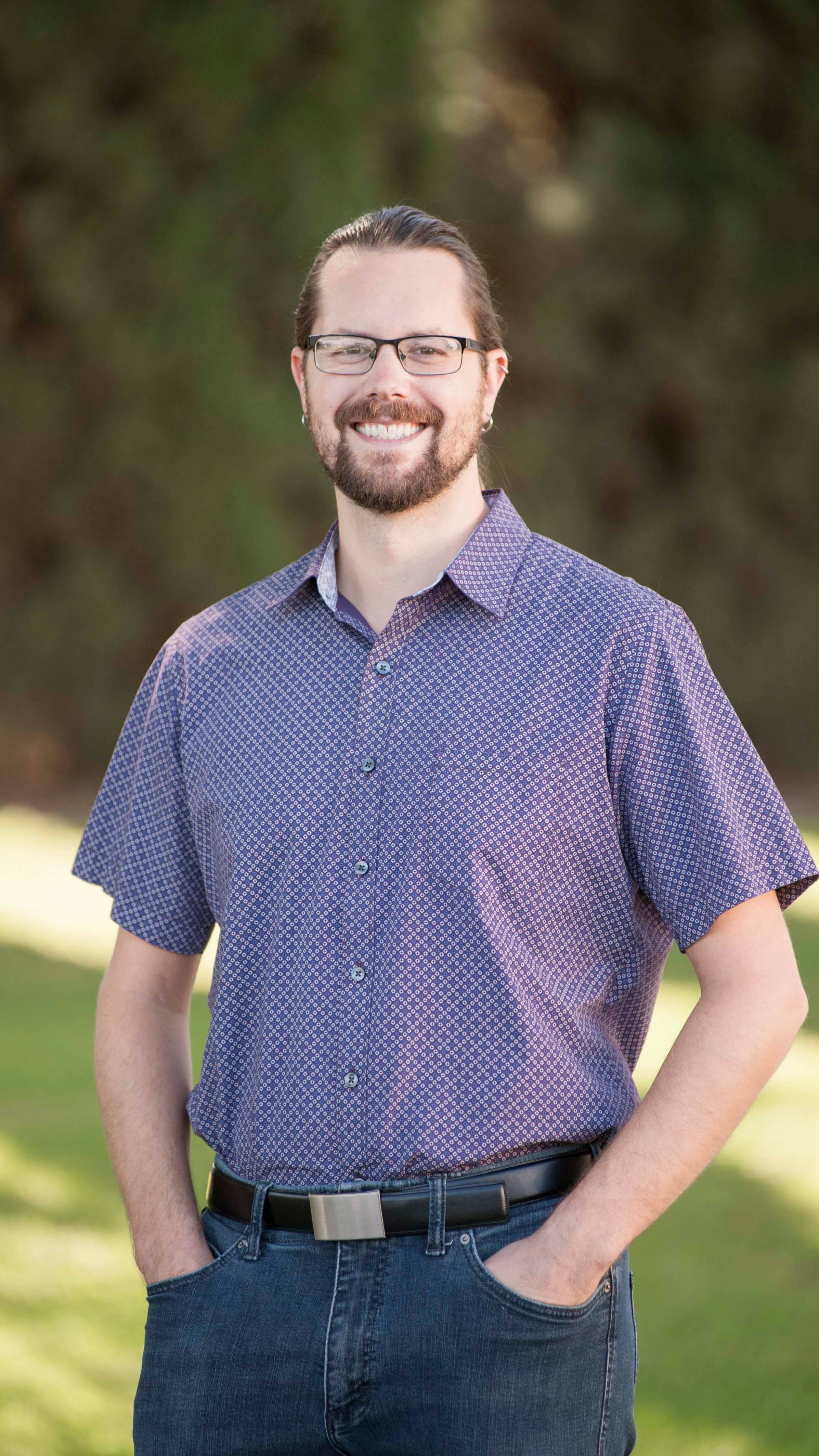 a person with glasses and a beard wearing a blue shirt