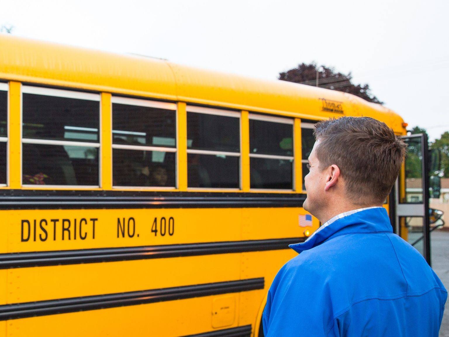 a person standing next to a school bus