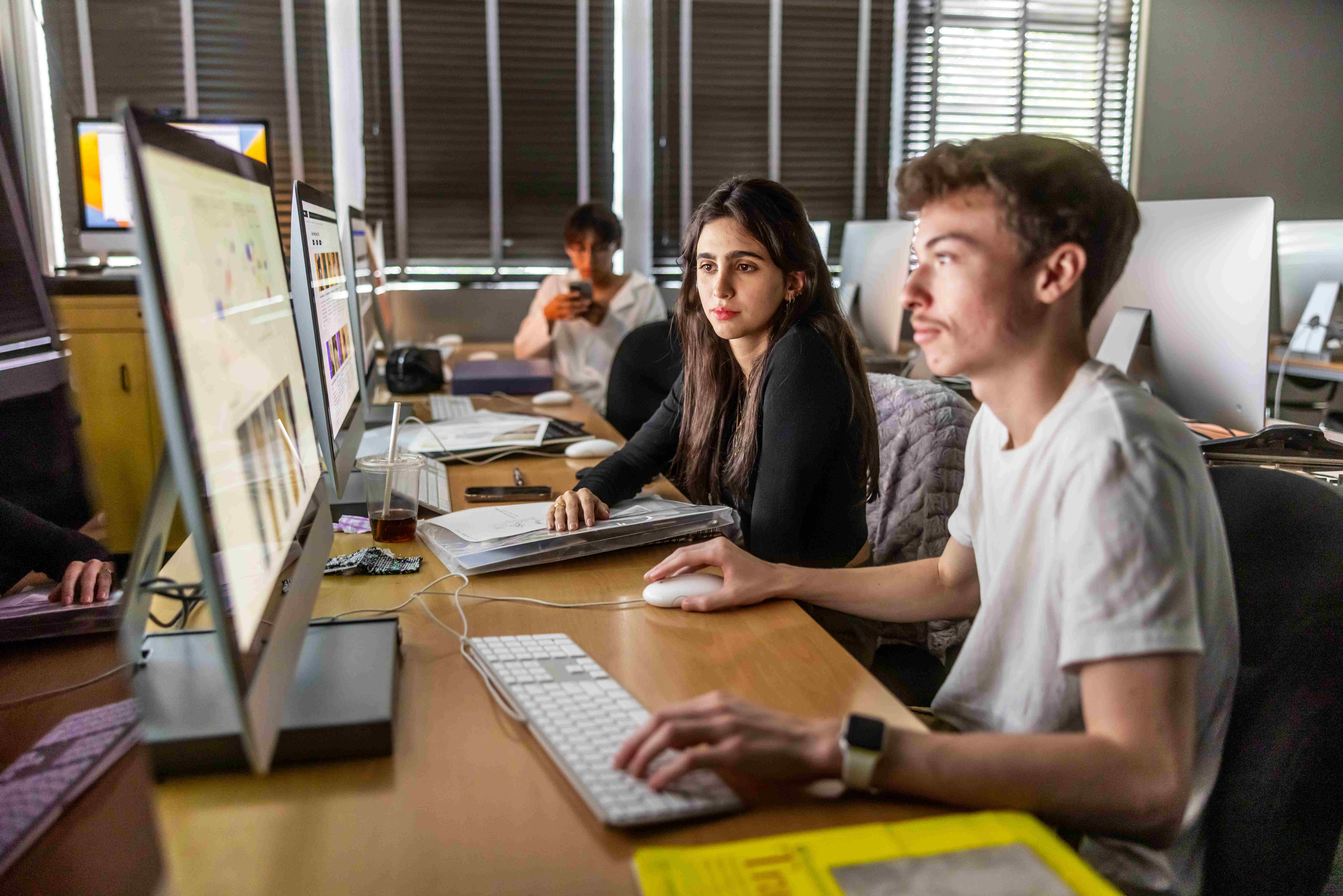 a group of people sitting at a desk with computers