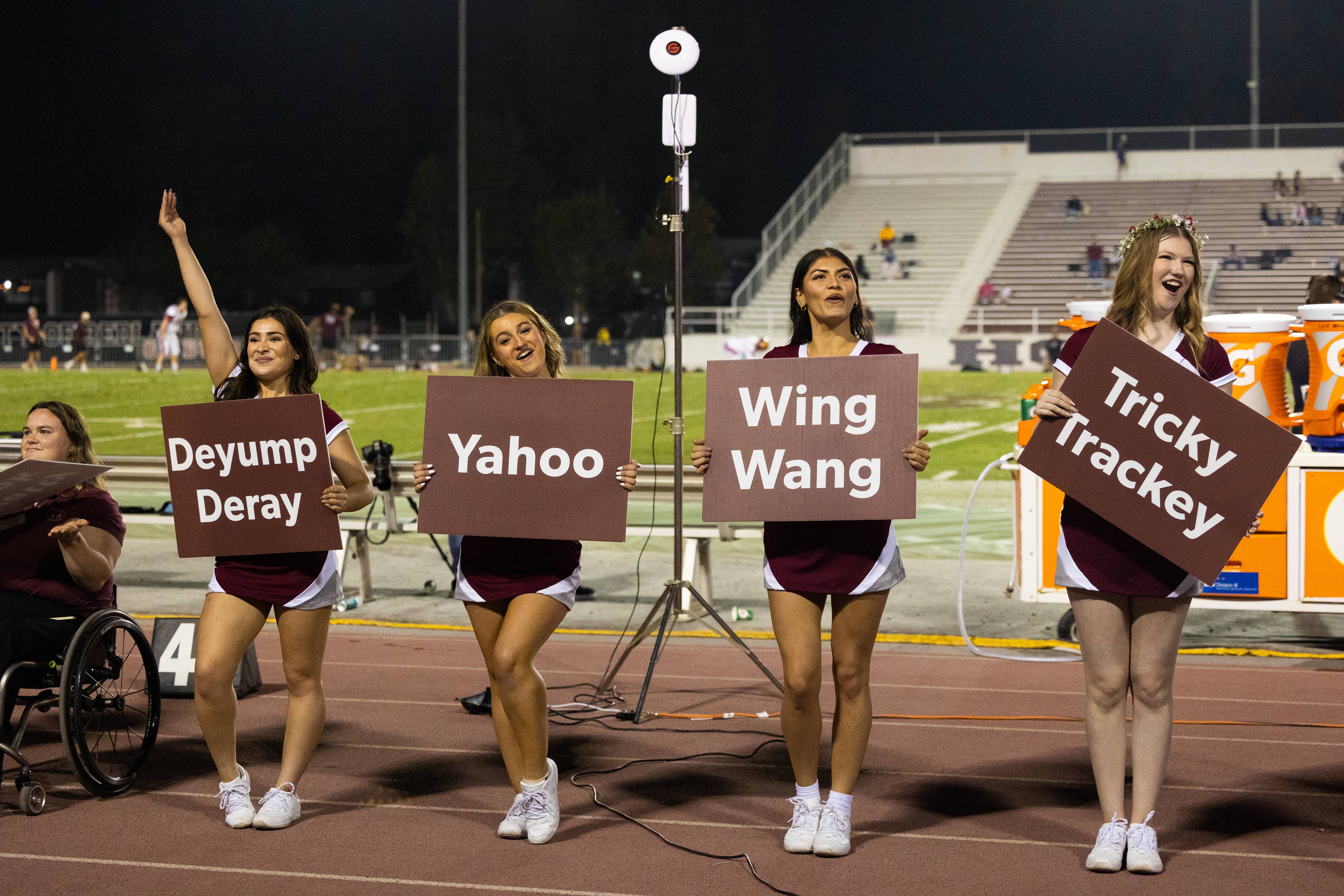 a group of cheerleaders holding signs on a track