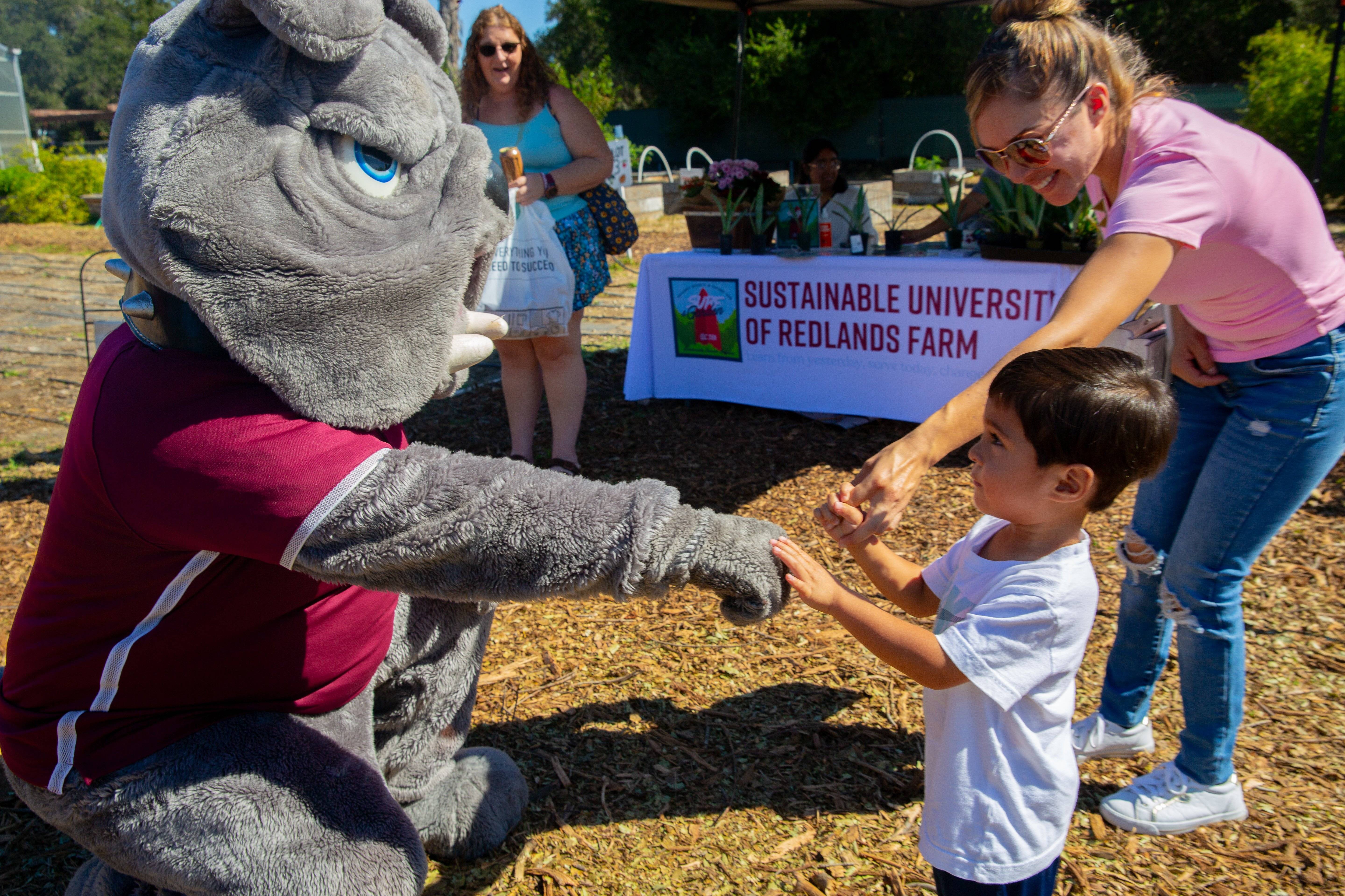 a person in a mascot garment holding a child's hand