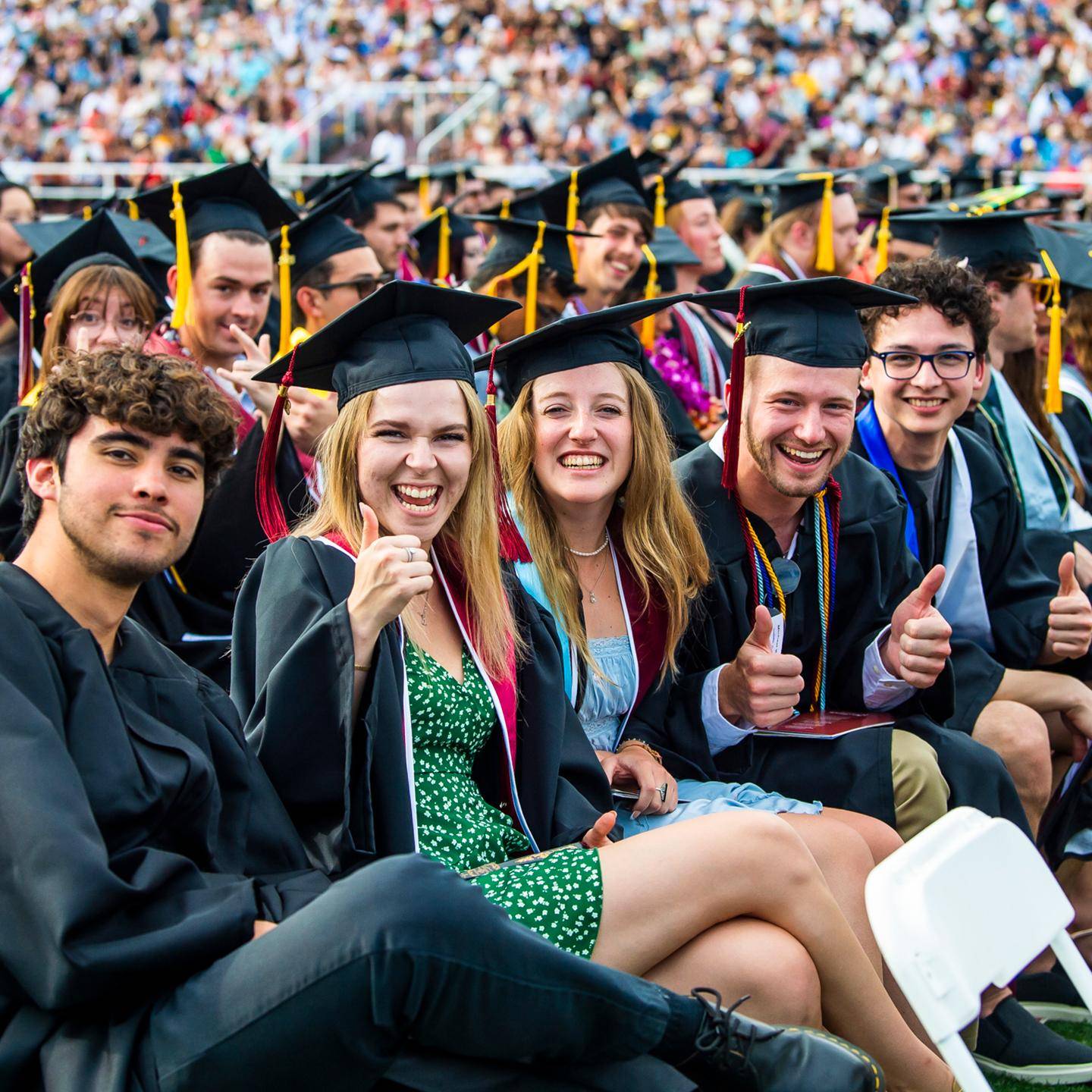 Redlands students giving a thumbs up in their caps and gowns.