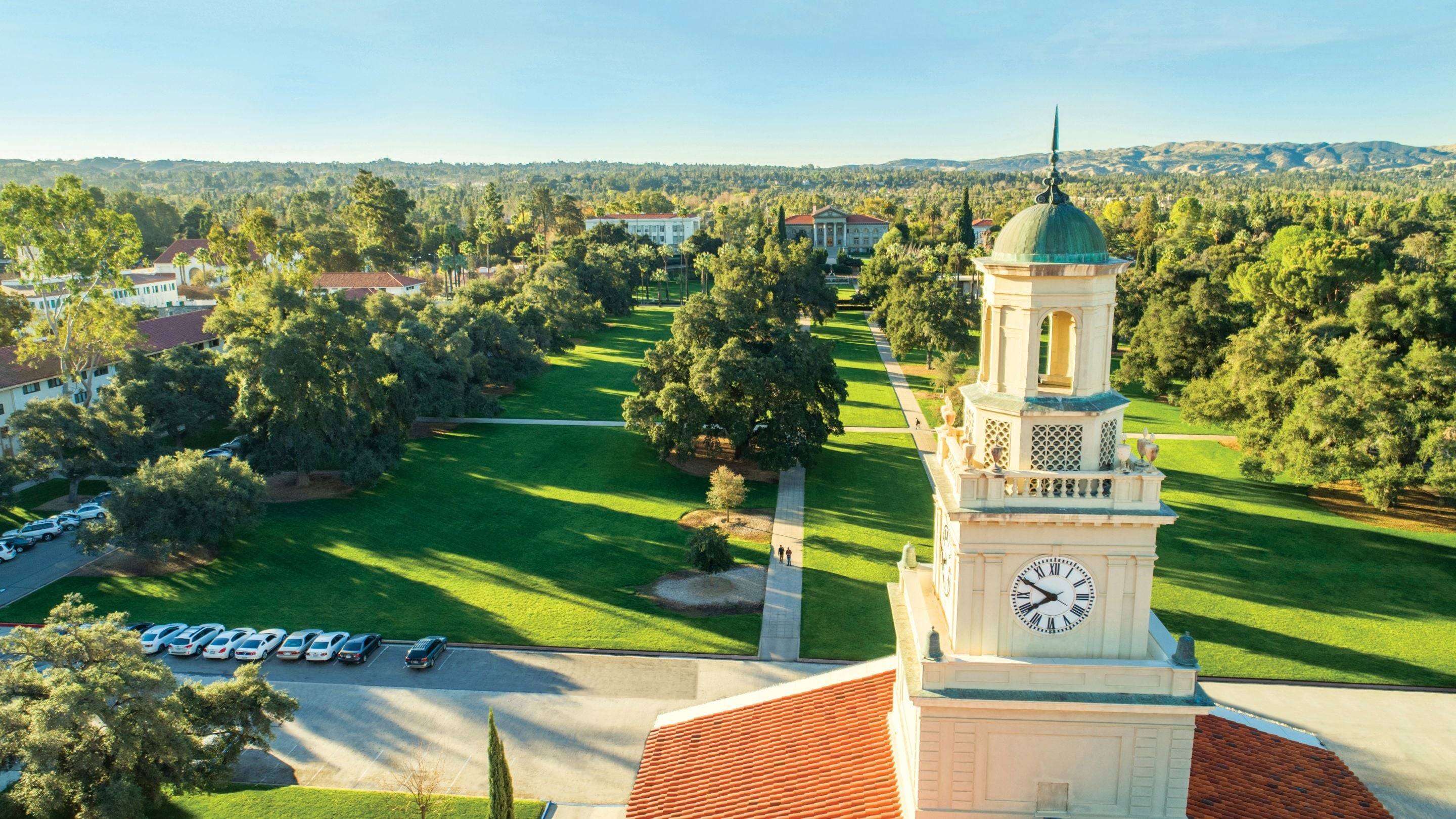 Aerial view of Memorial Chapel and green campus quad at University of Redlands with tree-lined walkways and surrounding buildings.