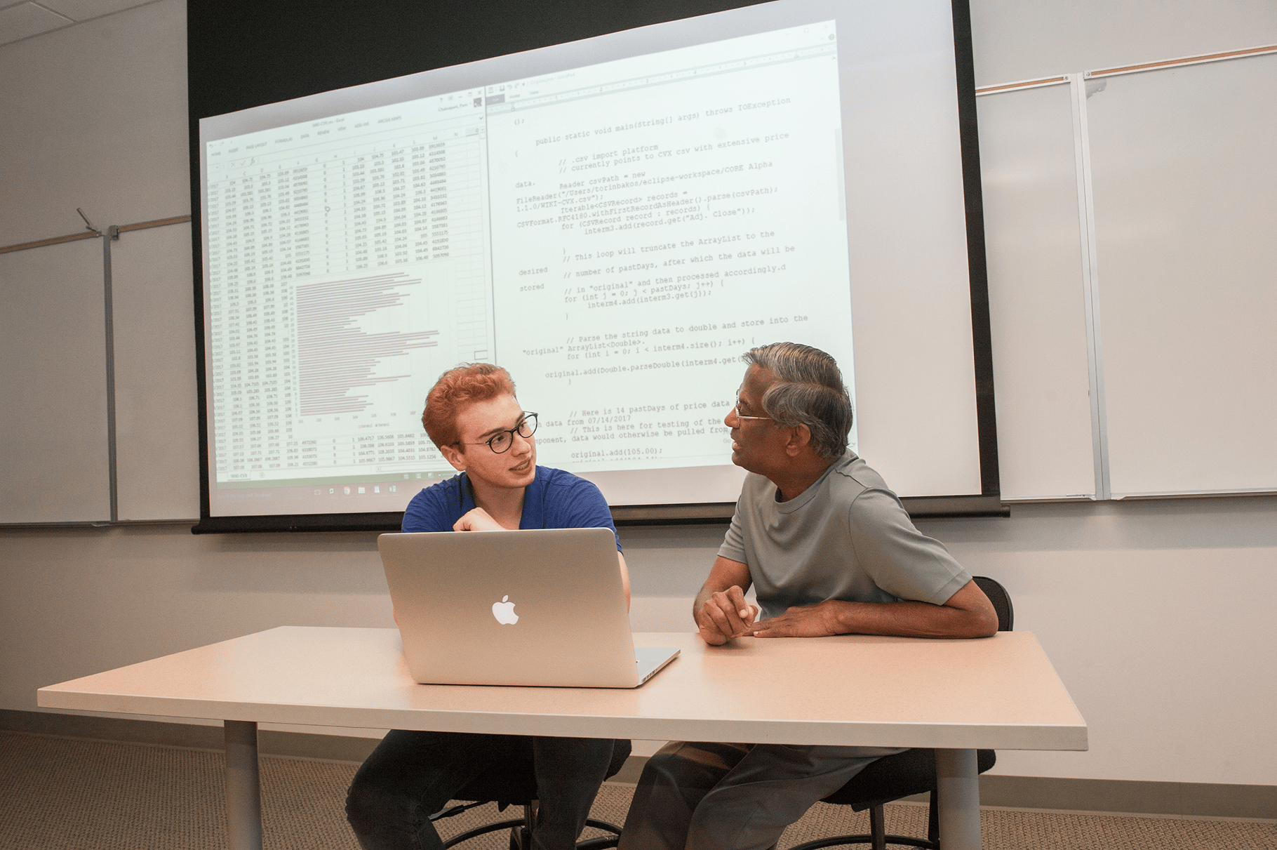 a person and person sitting at a table with a laptop