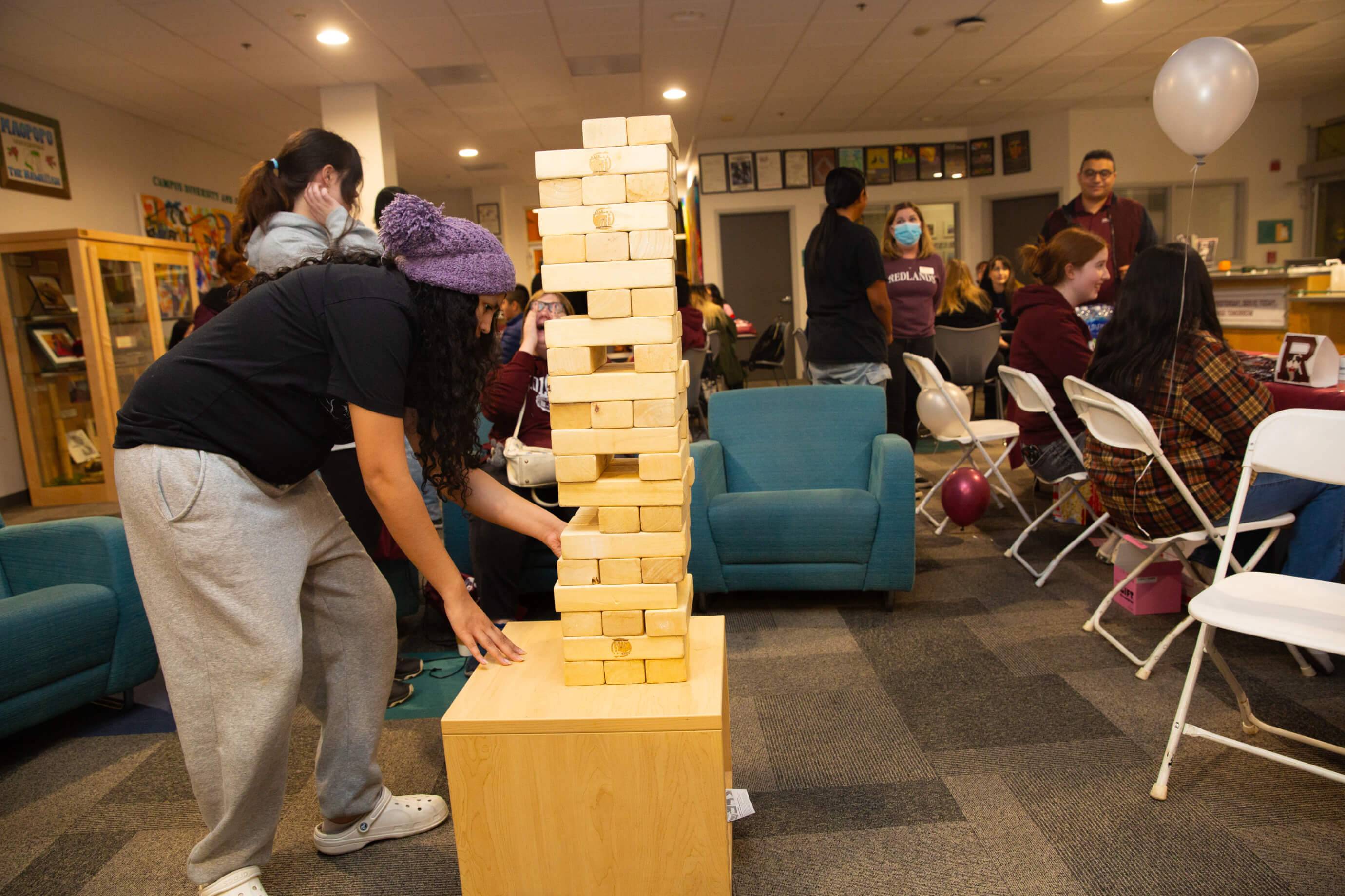 a person playing jenga in a room with other people