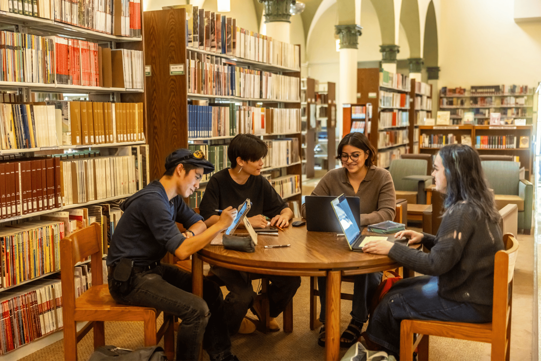 a group of people sitting around a table with laptops