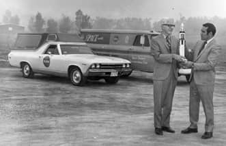 a person holding a rocket next to a couple of cars