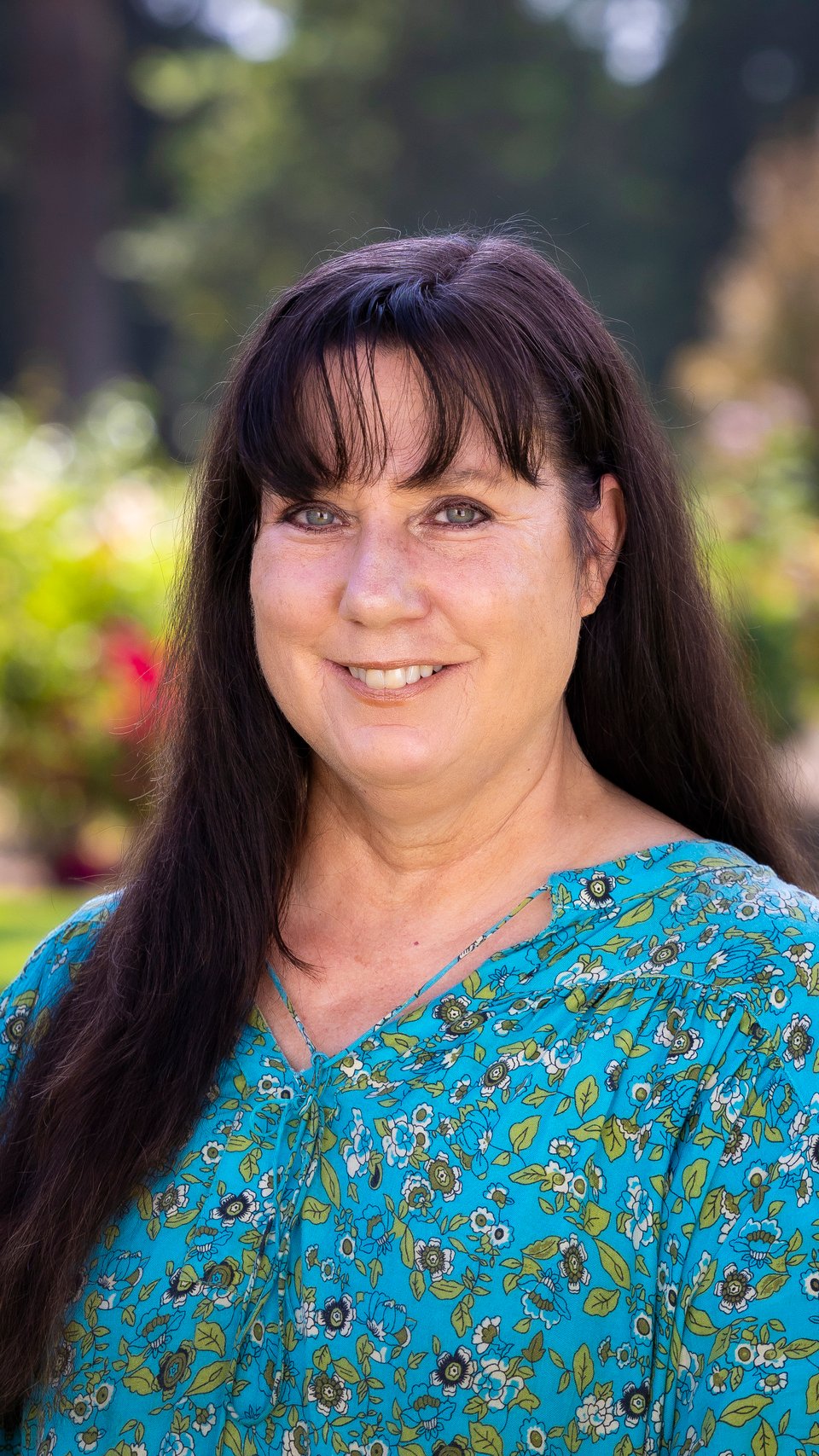 a woman with long hair wearing a blue floral shirt