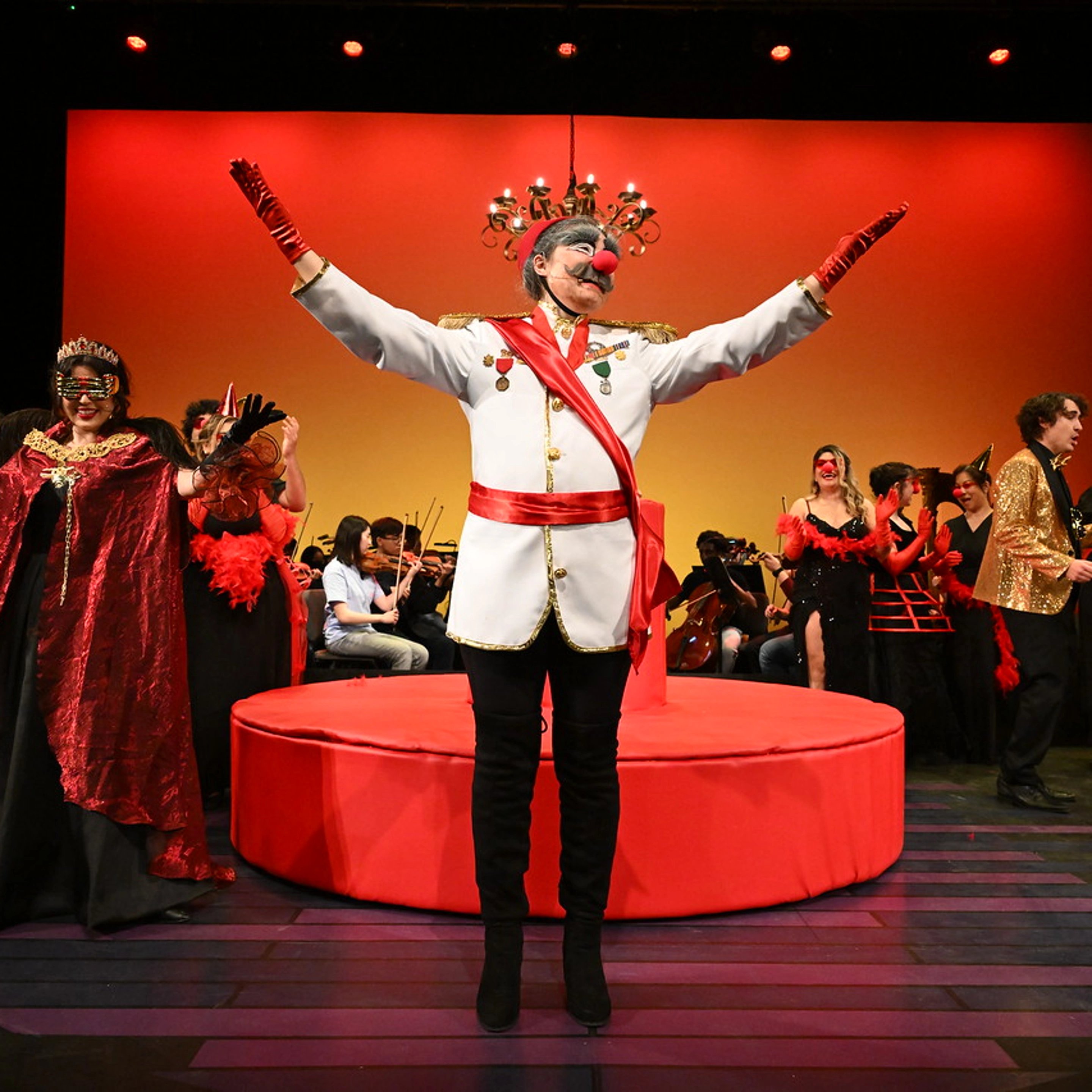a person wearing a mask and gloves on a stage with people in the background
