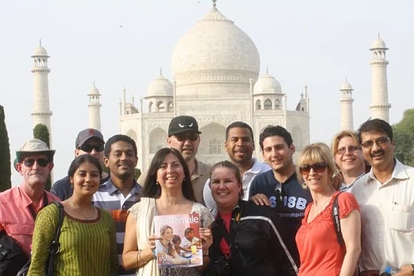 a group of people posing for a photo with Taj Mahal in the background