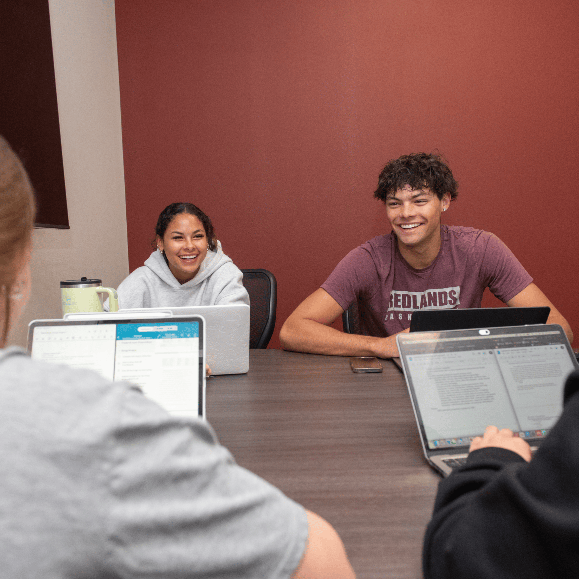 a group of people sitting at a table with laptops