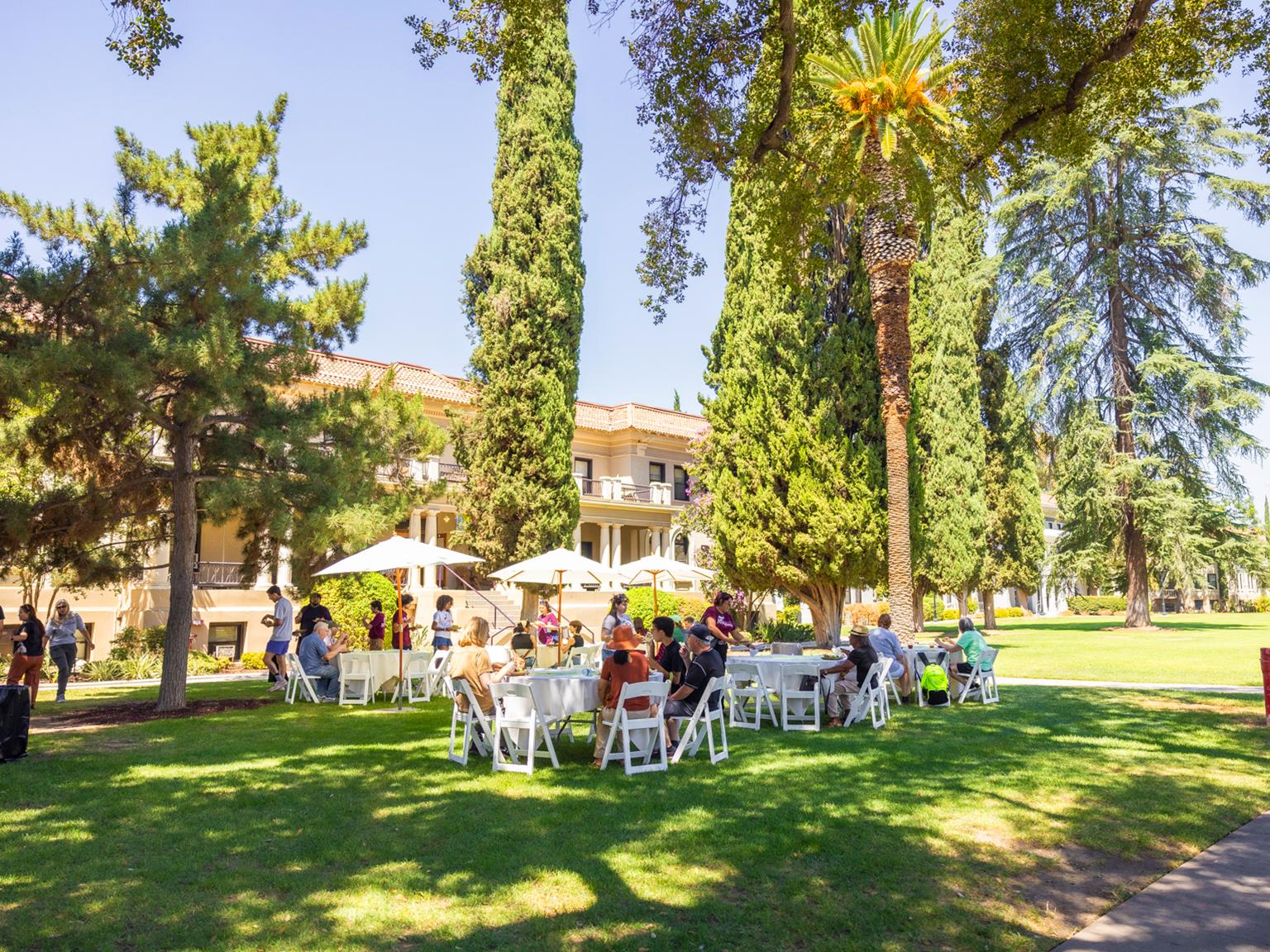 a group of people sitting at tables in a park