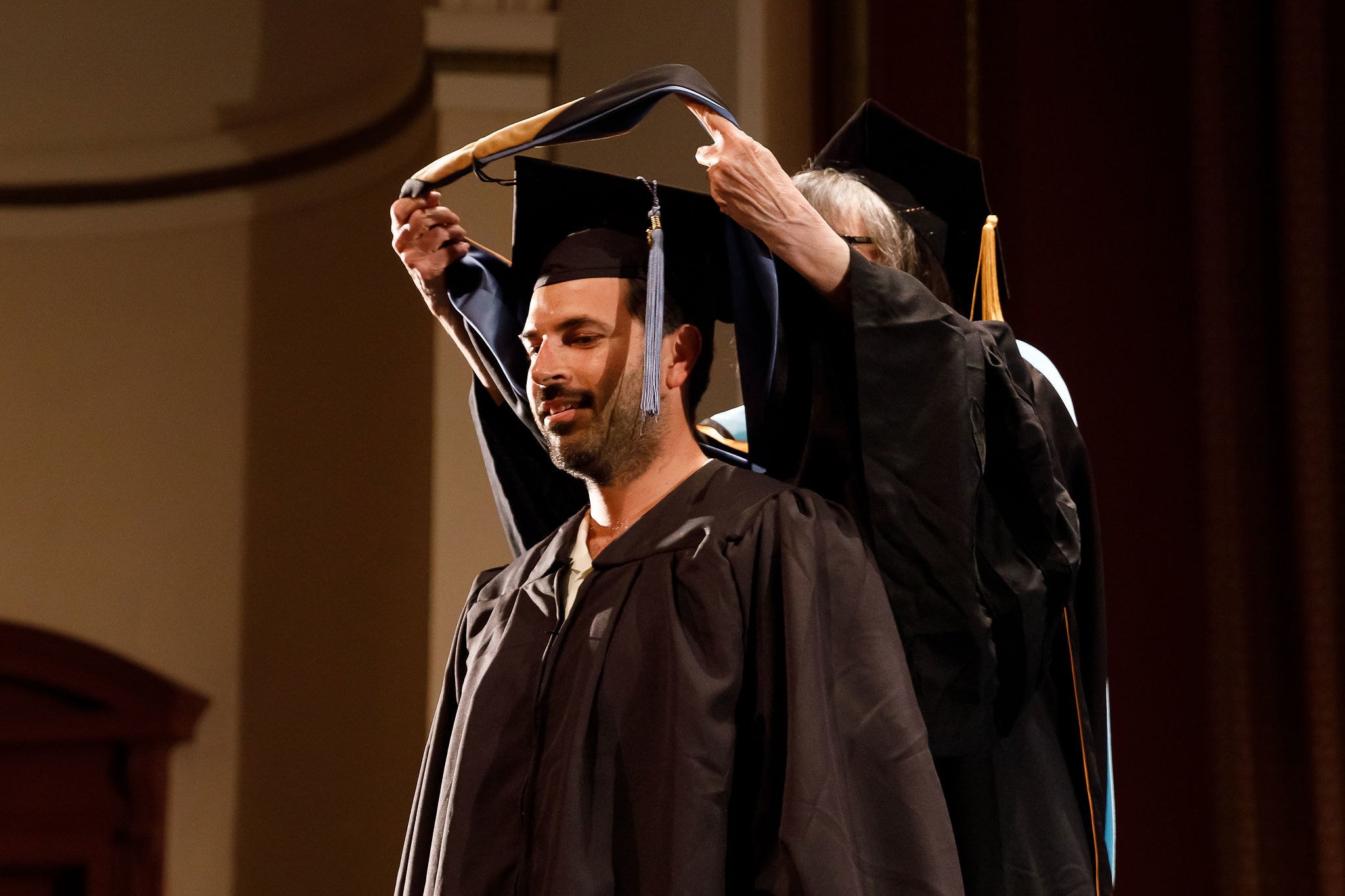 a man in a graduation gown holding a cap on his head