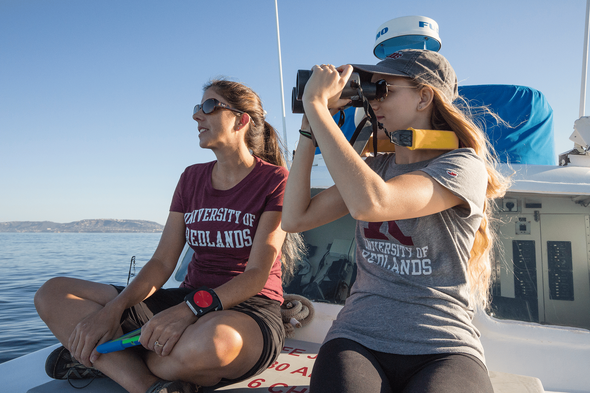 a couple of women on a boat looking through binoculars