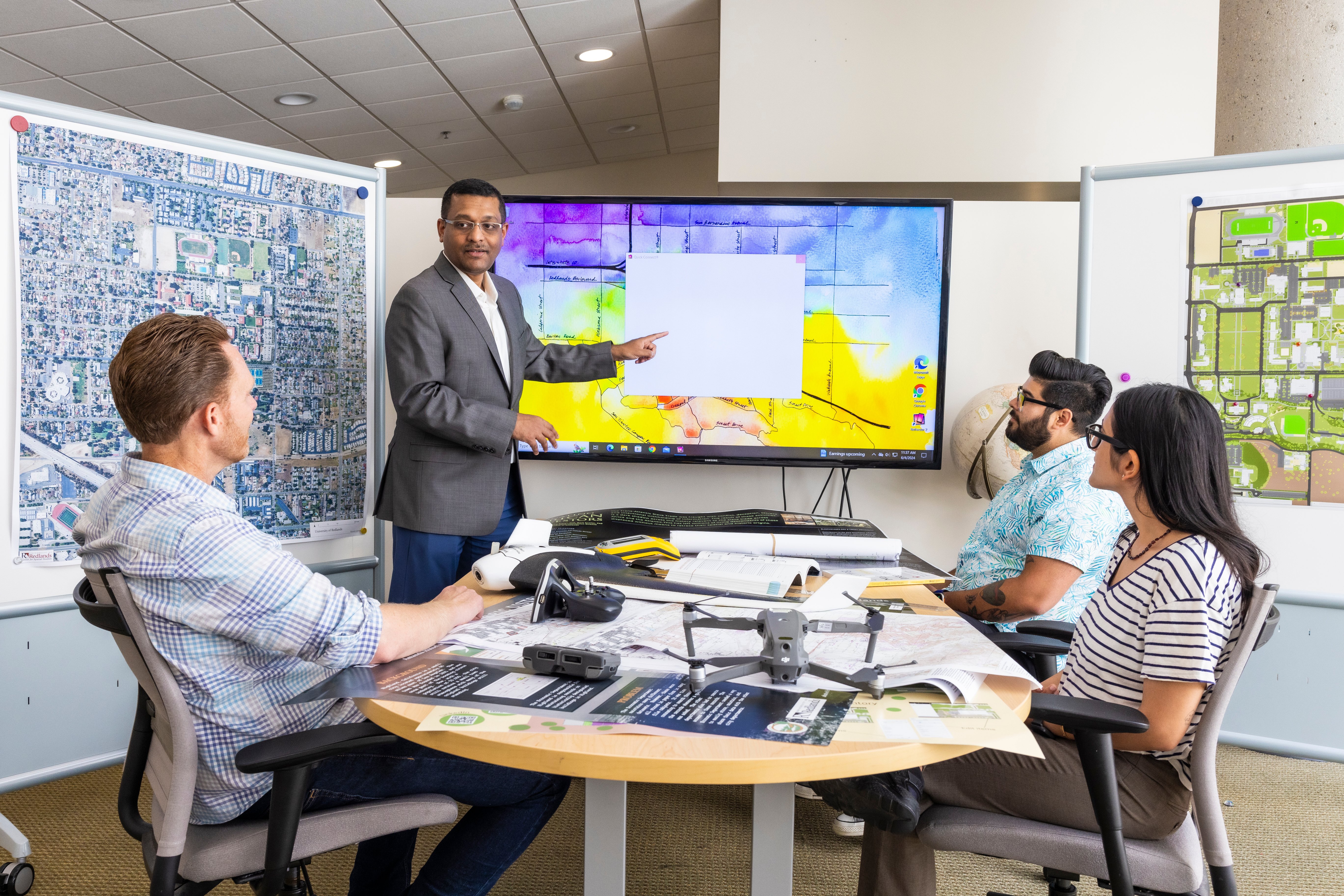 Students sitting around conference table while instructor is pointing at GIS map.