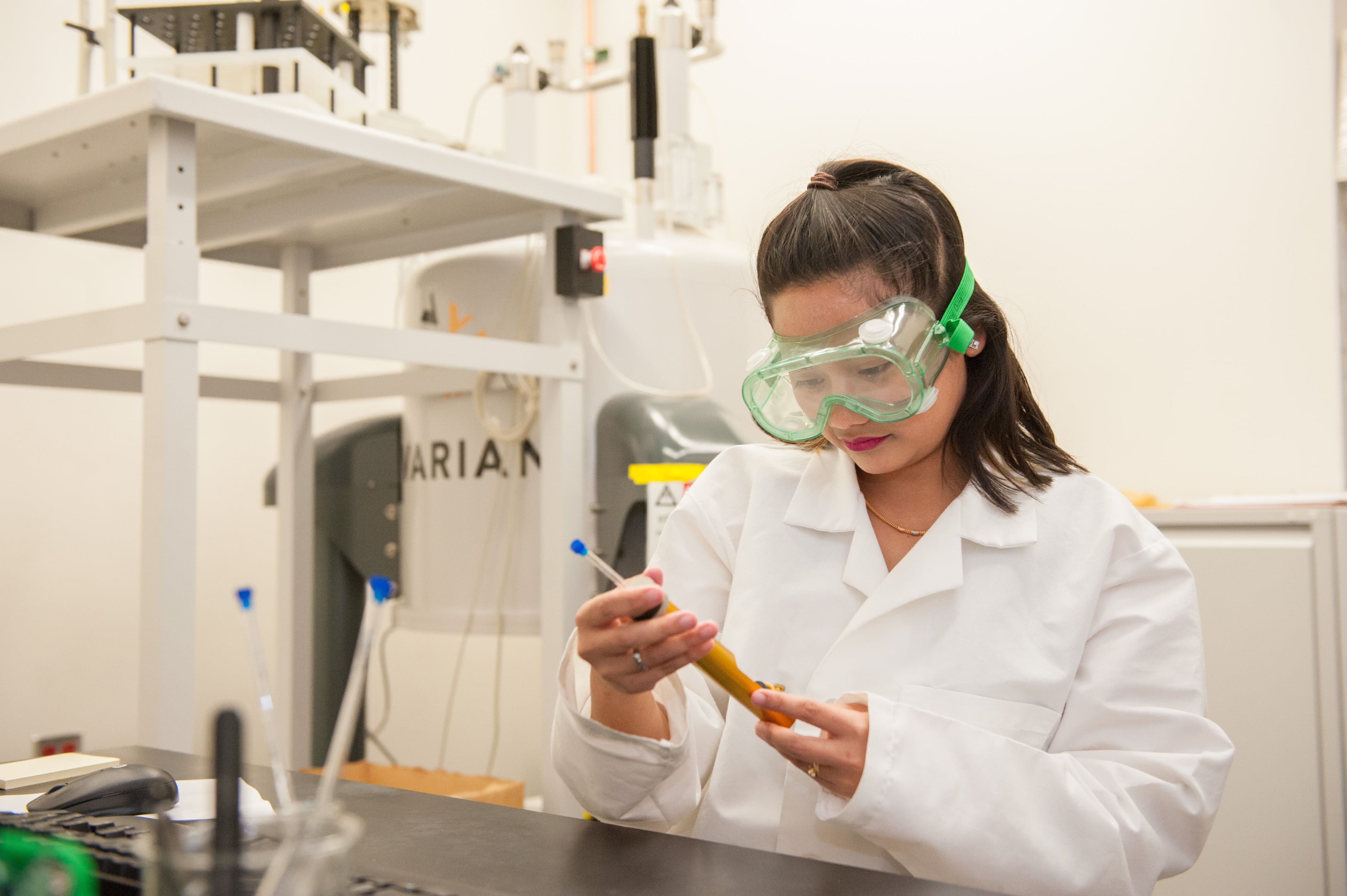 a person wearing safety goggles and holding a tube
