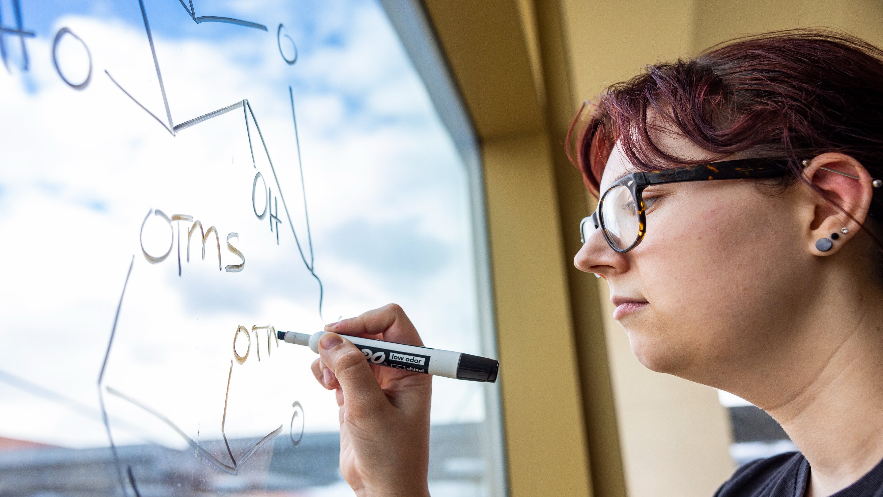 a person writing on a glass board