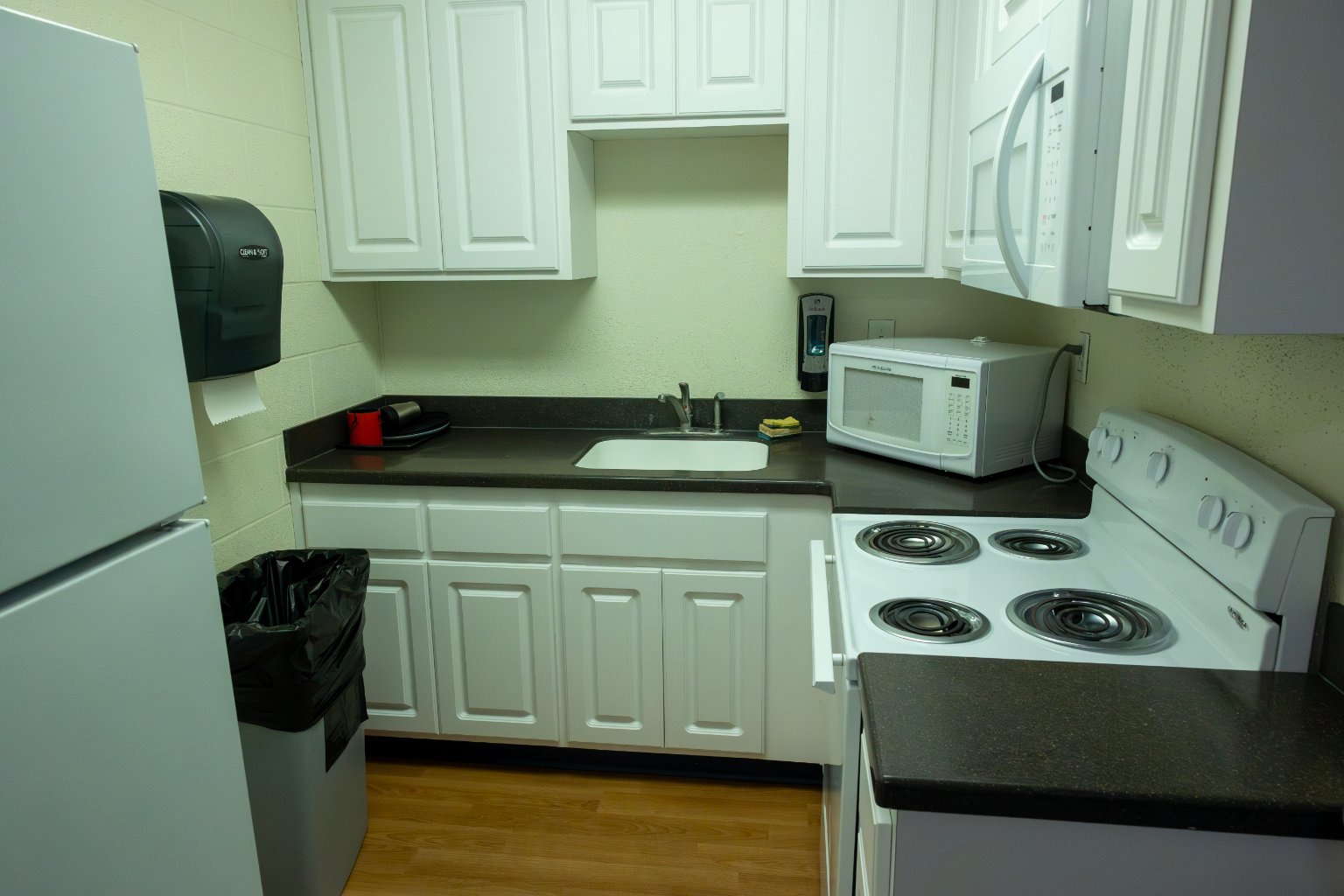 a kitchen with white cabinets and black counter tops