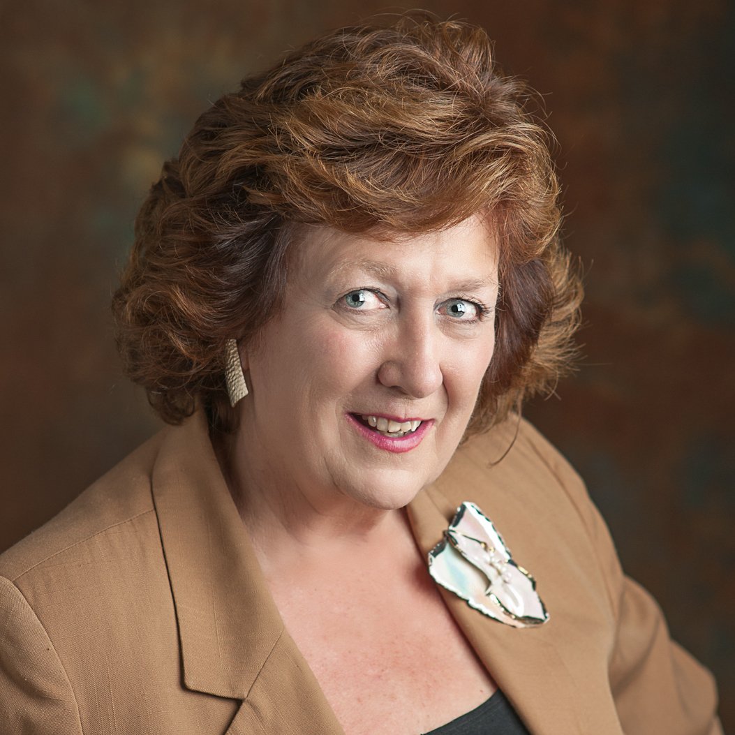 a person with short brown hair wearing a brown jacket