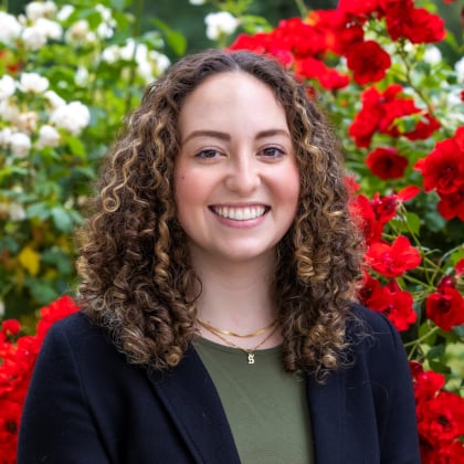 a person smiling in front of red flowers