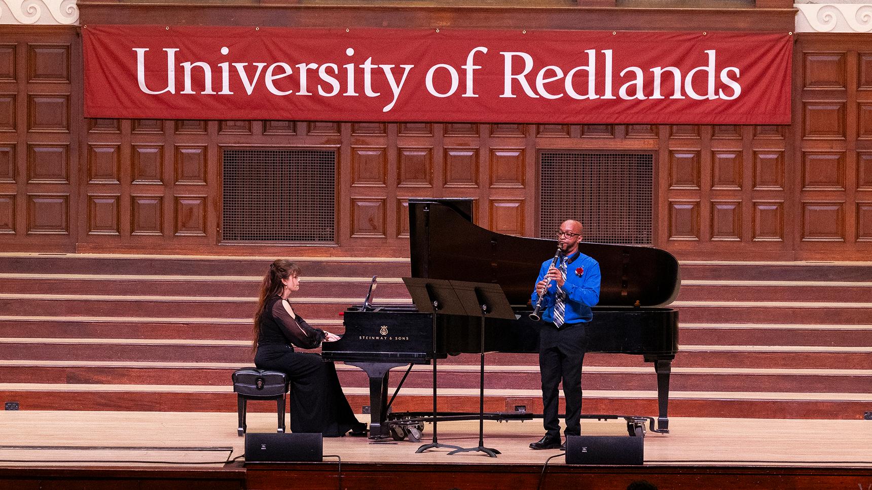 a person playing a flute on a stage with a person sitting on a piano
