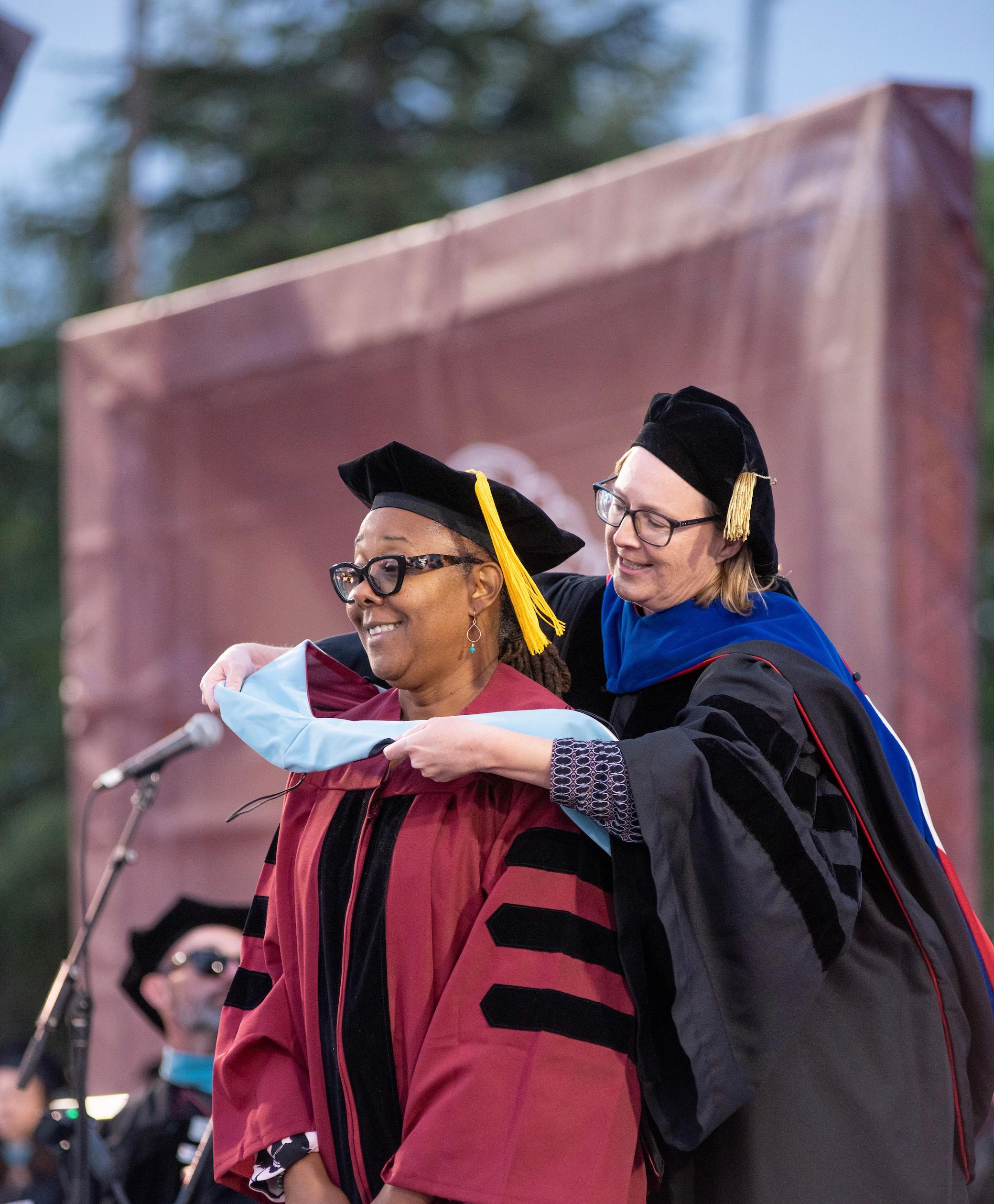 a woman hugging a woman in graduation gown