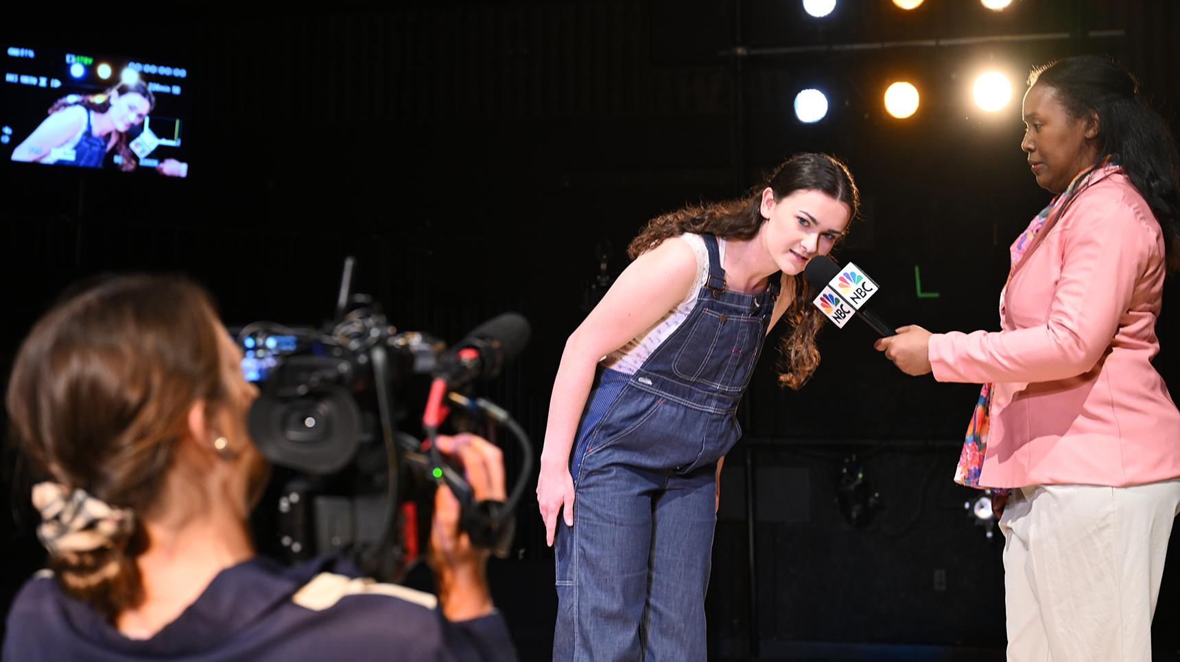 a person in overalls with a microphone in front of a camera
