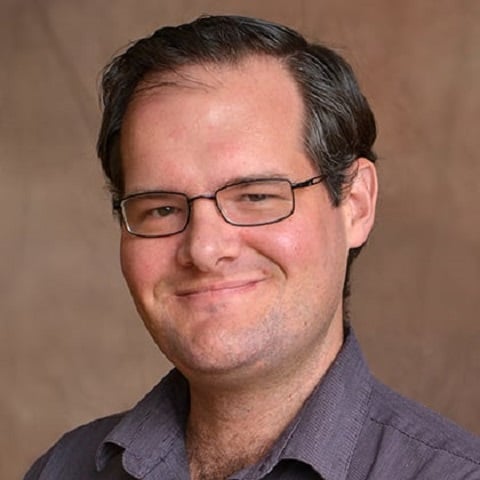 a man wearing glasses and a purple shirt