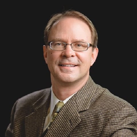 a person wearing glasses and a suit