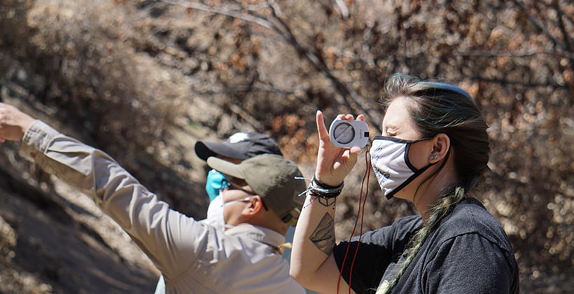 a woman wearing a face mask and holding a compass