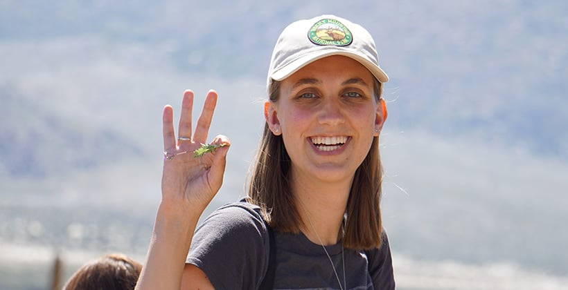 a woman holding up a small plant
