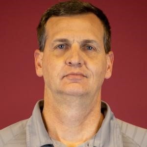 a person with short brown hair wearing a grey shirt