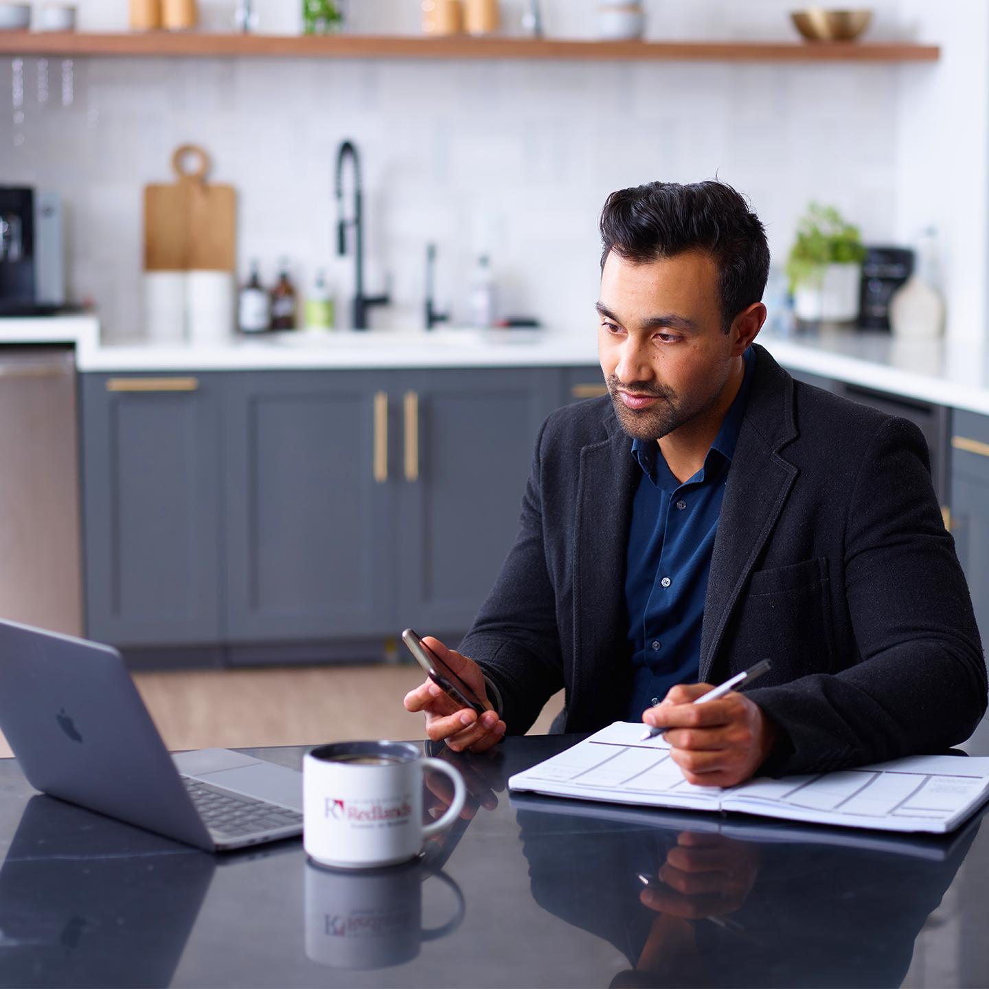 a person sitting at a table with a laptop and a phone