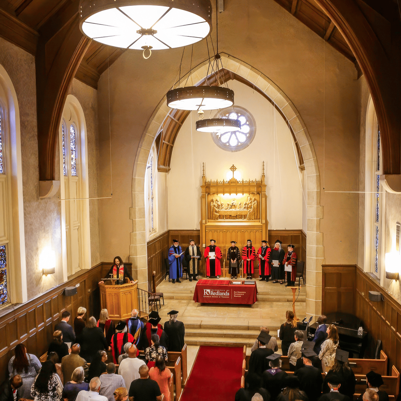 Friends and family standing up for Commencement at a chapel.
