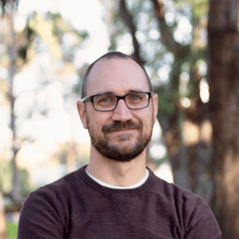 a man with glasses smiling