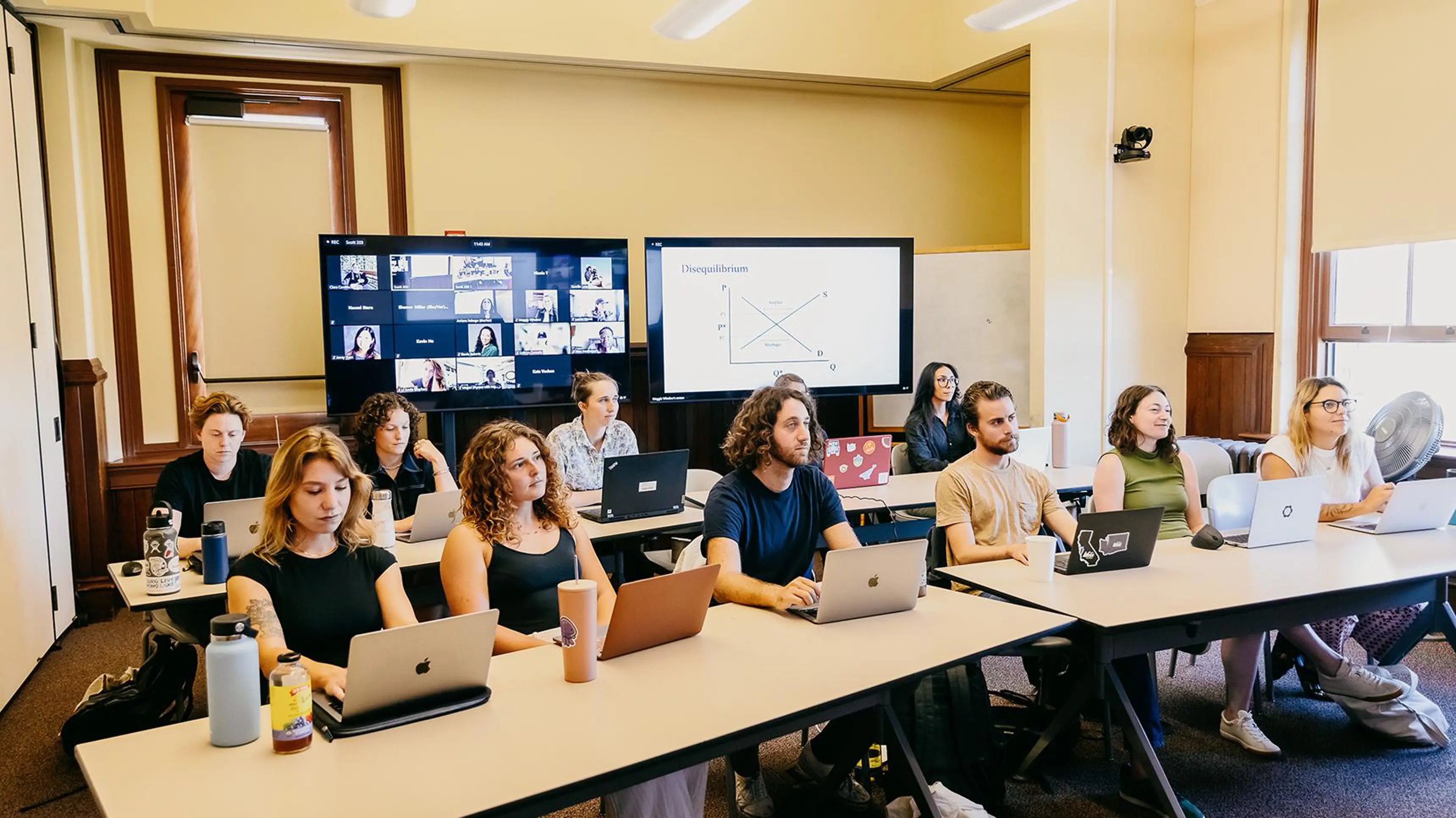 a group of people sitting at tables with laptops